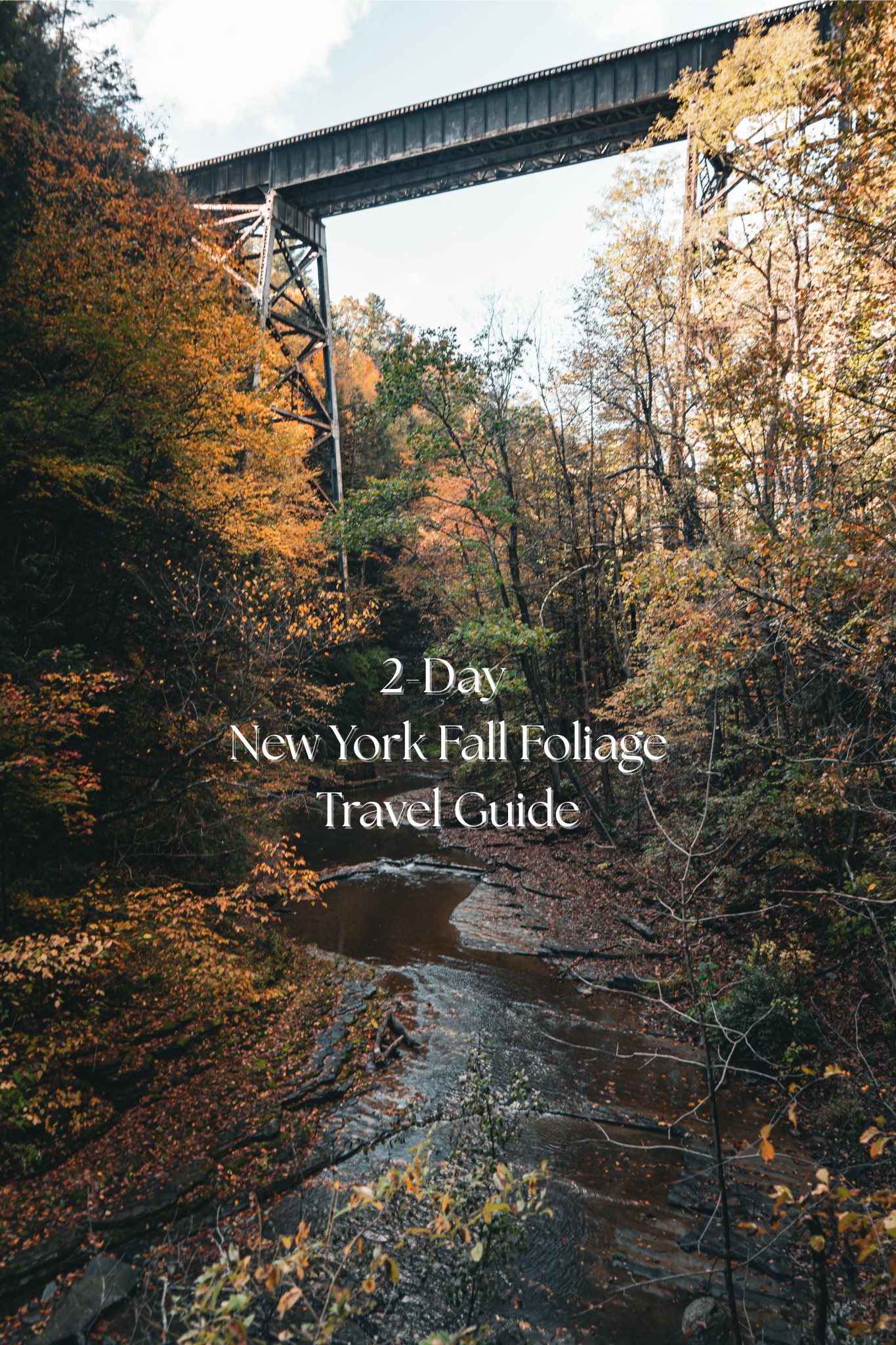 Autumn trees and a bridge over a river, text reads "2-Day New York Fall Foliage Travel Guide" on a serene fall landscape.