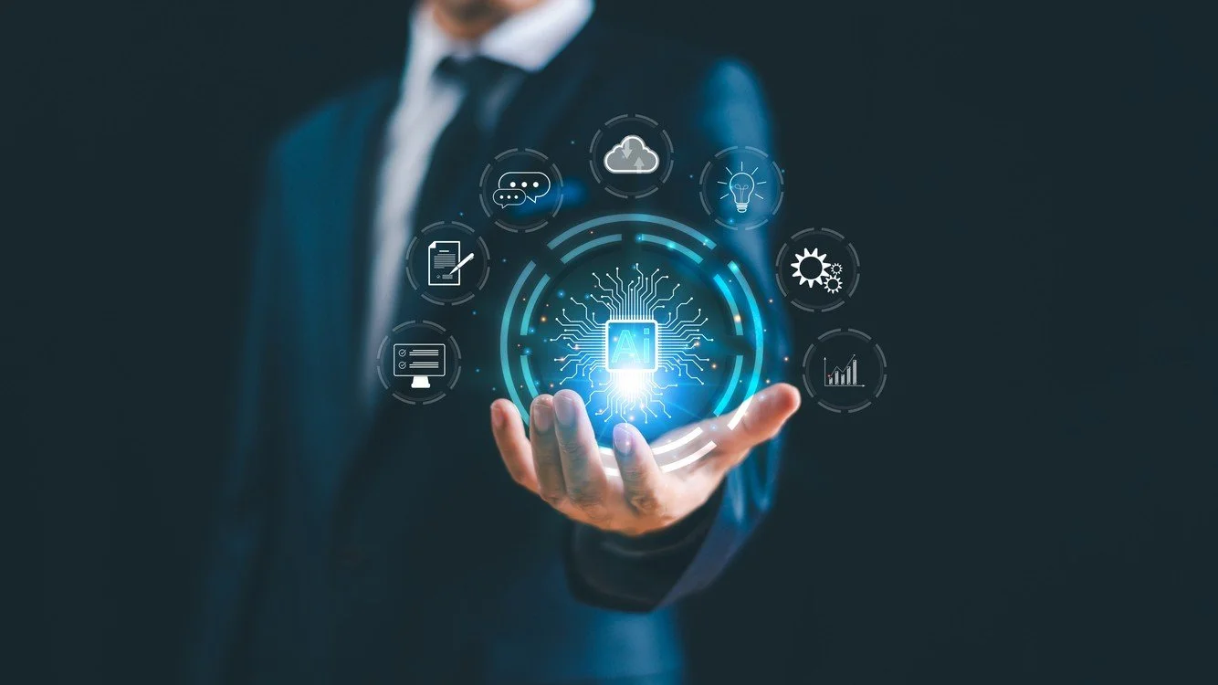 A businessman in a suit holding a holographic interface with AI-related icons, including cloud computing, lightbulb, gears, graph, survey, chat, and document icons.