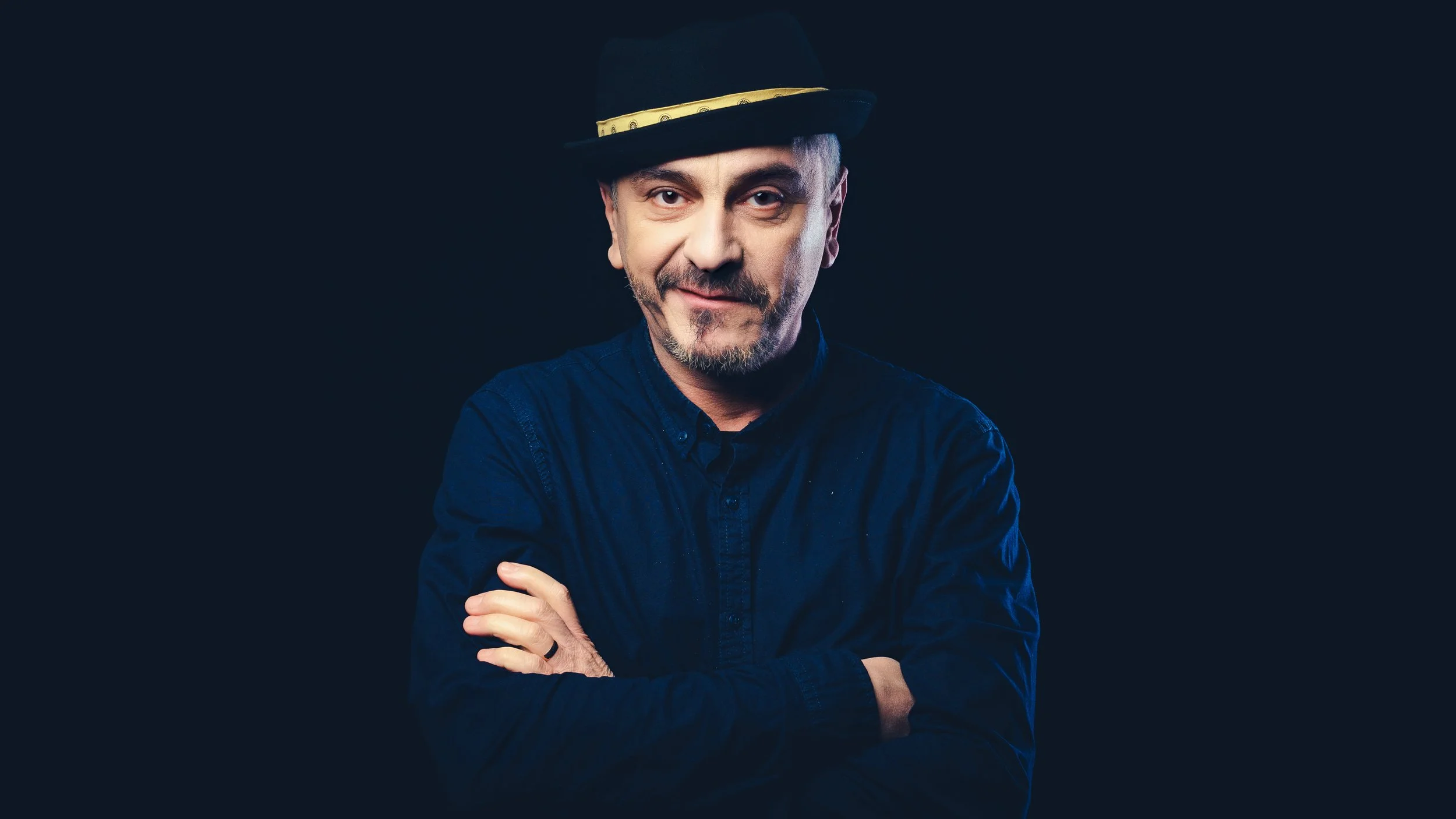Professional studio headshot of an actor in a dark top, focused on a natural, expressive theatrical gaze.