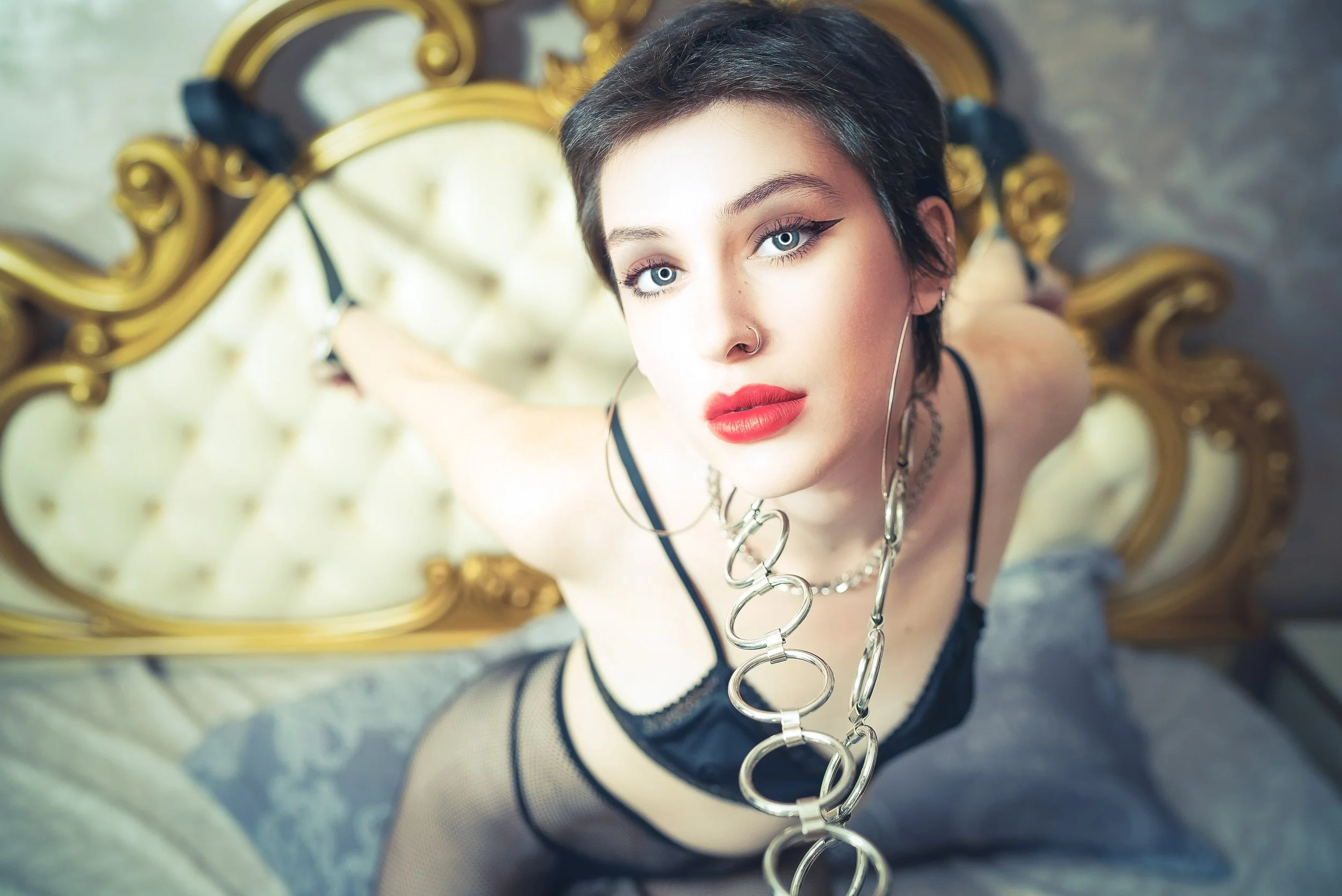 Intimate studio boudoir portrait utilizing dramatic shadows and creative props in a golden-toned bedroom setting.