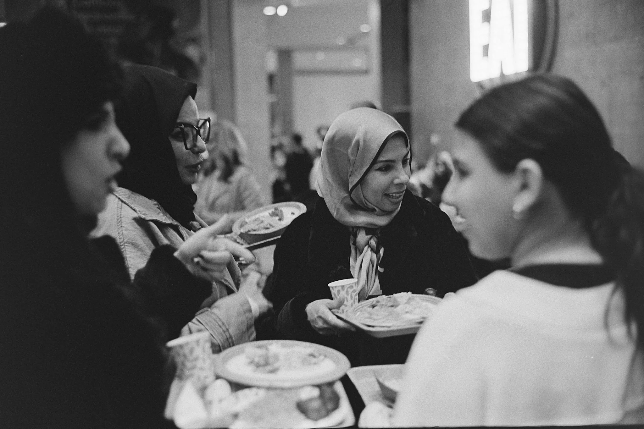 Four women of diverse backgrounds sitting together at a table in a restaurant, sharing a meal and engaging in conversation.