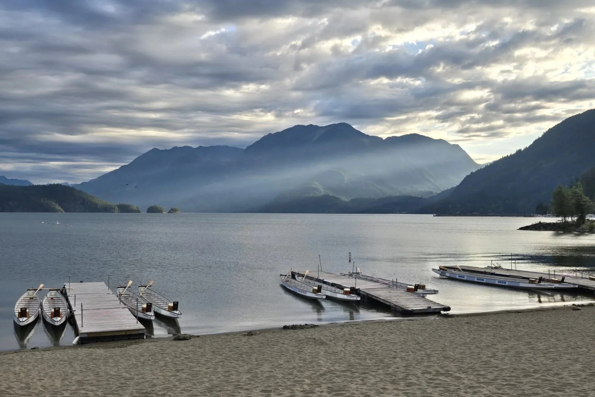 Dragon boats rest at the docks on calm morning water of Harrison Lake