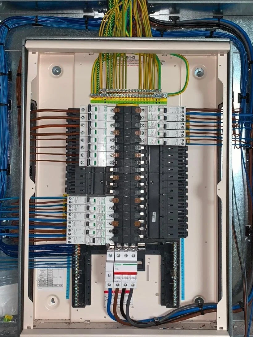 Electrical control panel with wiring, circuit breakers, and switches inside a metal enclosure.