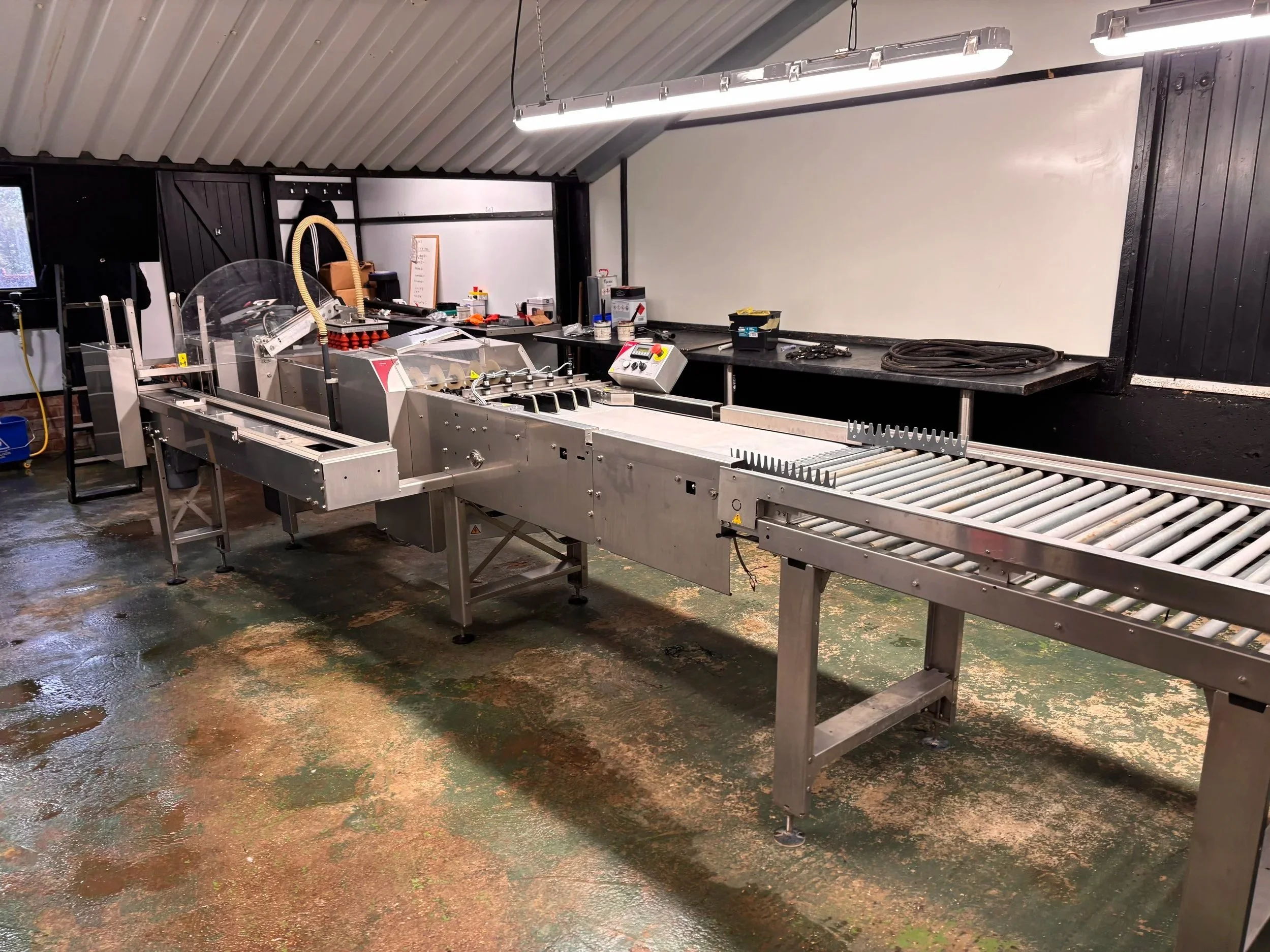 Industrial food processing conveyor system inside a factory with wet and stained floor.