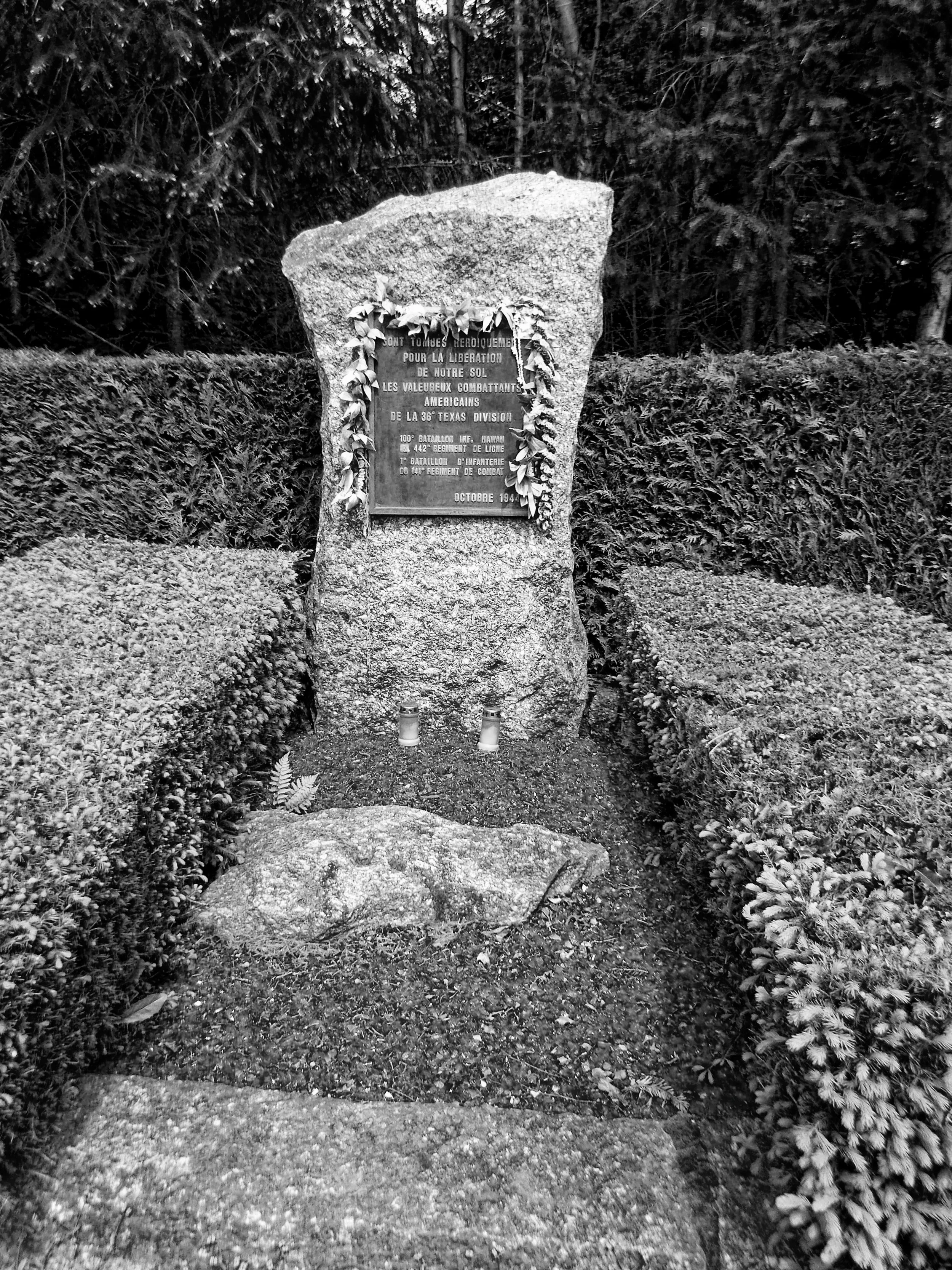 The monument for the rescue of the Texas “Lost Battalion.” The island of Oahu is lying in blue glass, leis of flowers and shells adorn the stone. Photo by Wendy Noritake.
