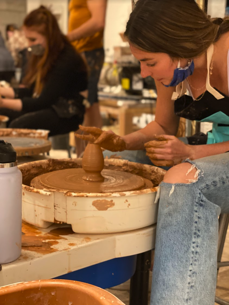 Student throwing a clay pot on the wheel