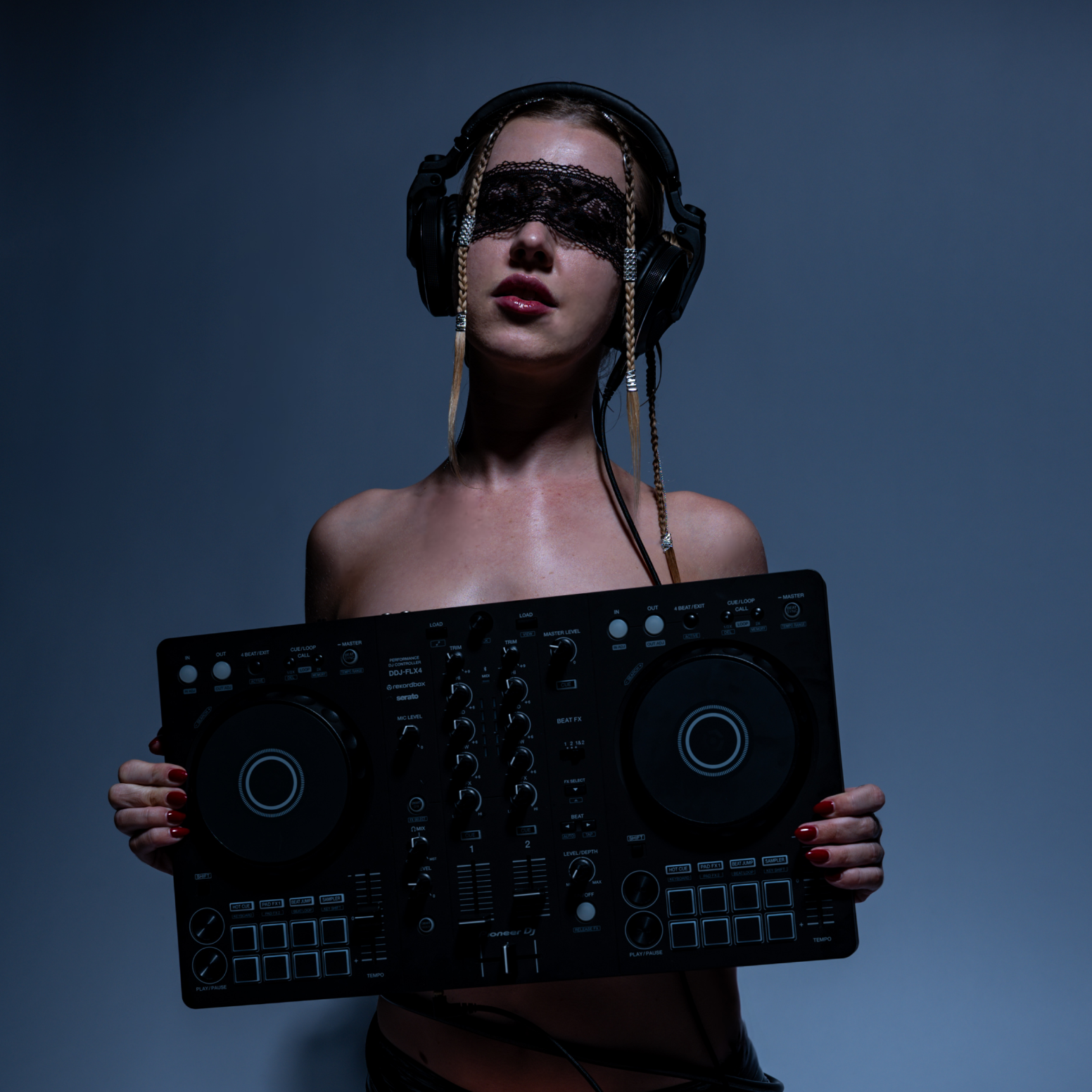 Topless Claire De Lune wearing headphones and a black lace eye mask holding a DJ mixer against a dark blue background.