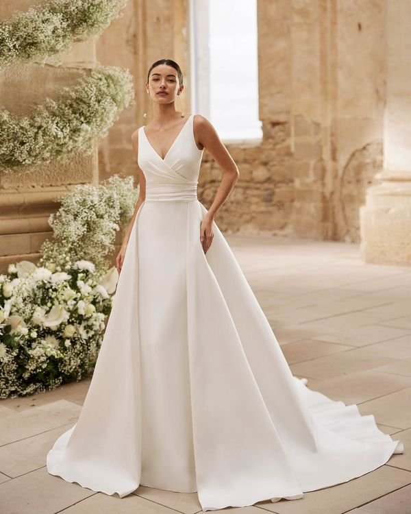 Bridal gown, mermaid silhouette. Made of bi-stretch crepe with a V-neckline. Straps, V-back, and detachable overskirt included.