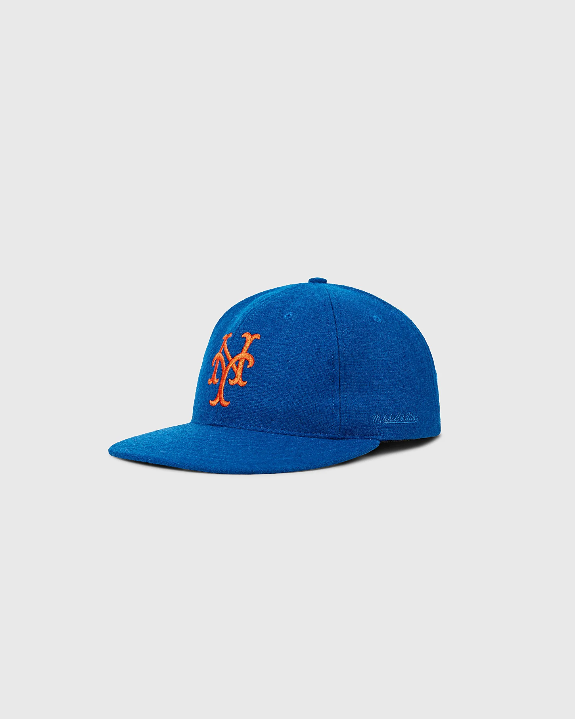 Blue baseball cap with orange embroidered New York Mets logo and white signature on the side, against a plain light gray background.