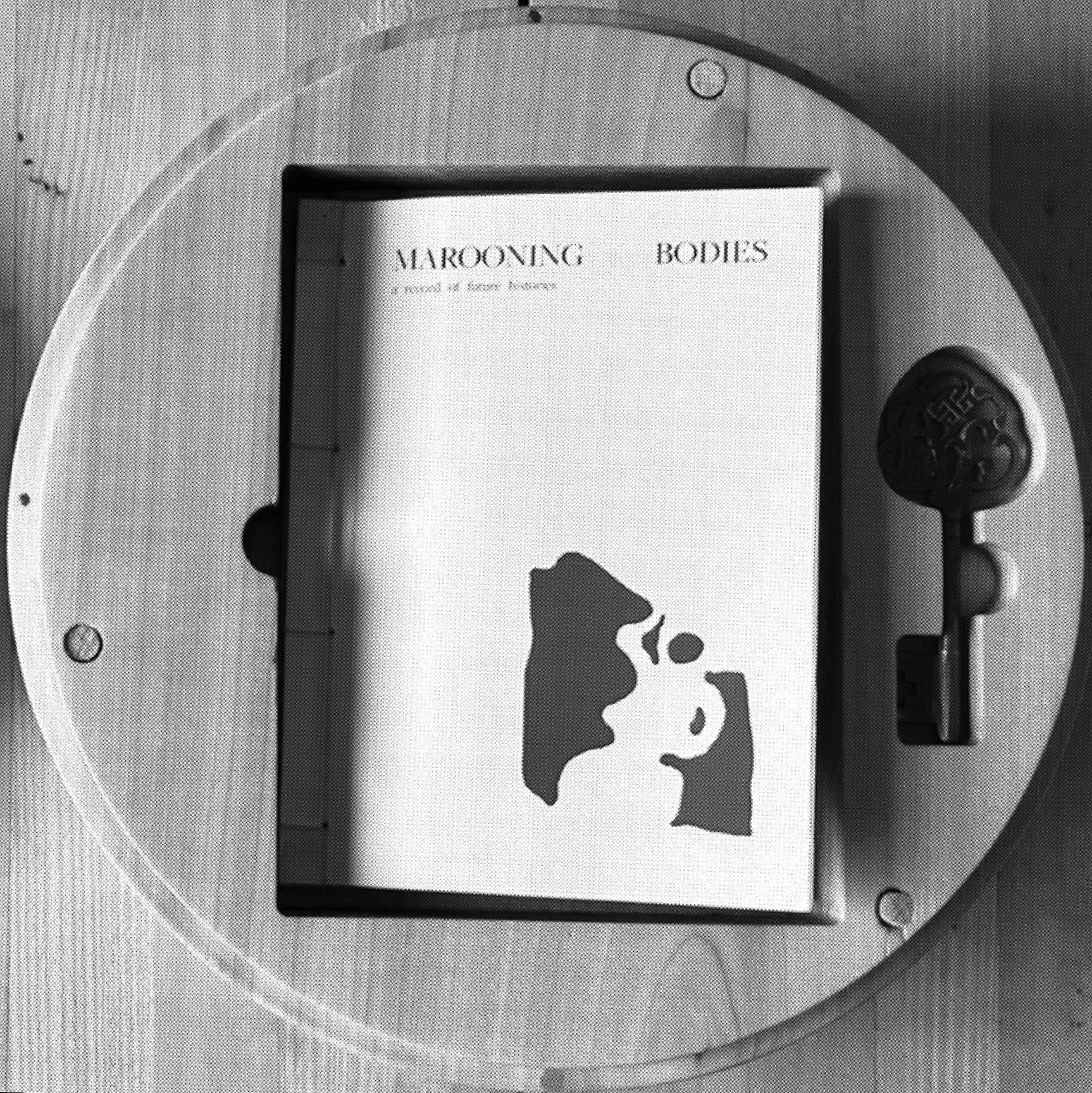 Book titled 'Marrowng Bodies: A kind of body story' lying inside a circular glass display case with a key nearby.