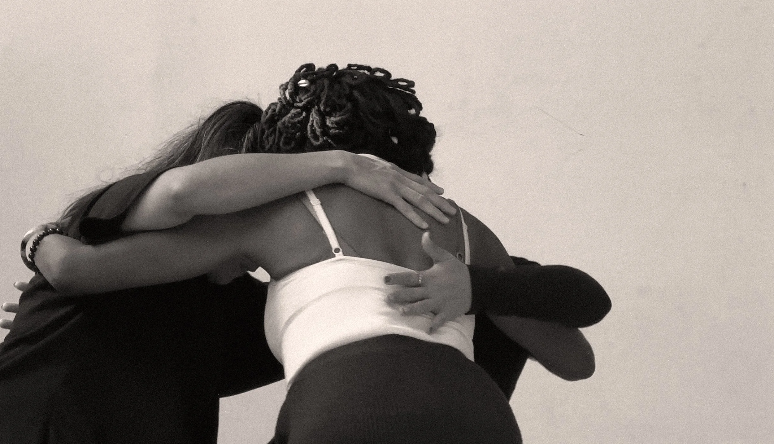 Two people hugging each other with one person resting their head on the other's shoulder, their arms wrapped around each other.