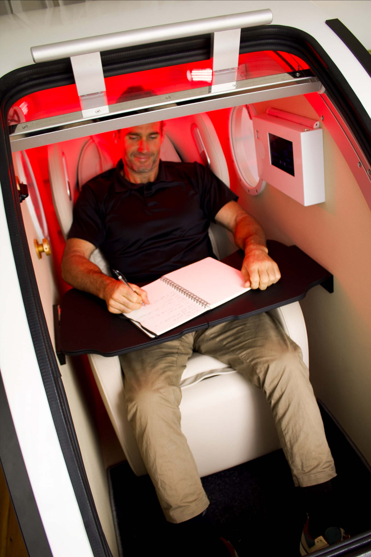 Client working inside seated 2.0 ATA mild hyperbaric oxygen therapy chamber at Airox Wellness Lennox Head.