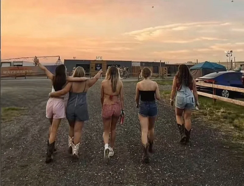 Friends walking together outdoors during sunset, enjoying a casual moment near an open landscape with a warm evening sky in the background.