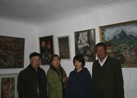 Four people standing in front of a wall decorated with various paintings in an art gallery.