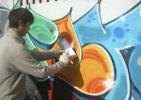 A person painting bright, colorful graffiti on a wall.