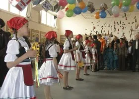Children dressed in festive costumes participating in a celebration with balloons and decorations