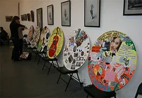 Art exhibition with circular mosaic artworks displayed on easels in a gallery.