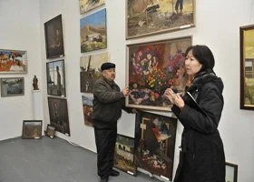 Two women viewing paintings in an art gallery, with various landscape and floral artworks on the walls.