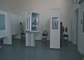 People in an art gallery observing artwork and displays.
