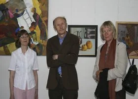Three people standing in an art gallery with paintings on the wall