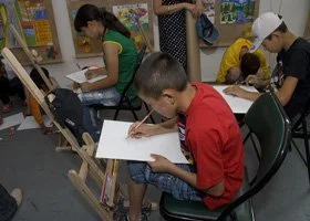 Children drawing at easels in an art classroom.