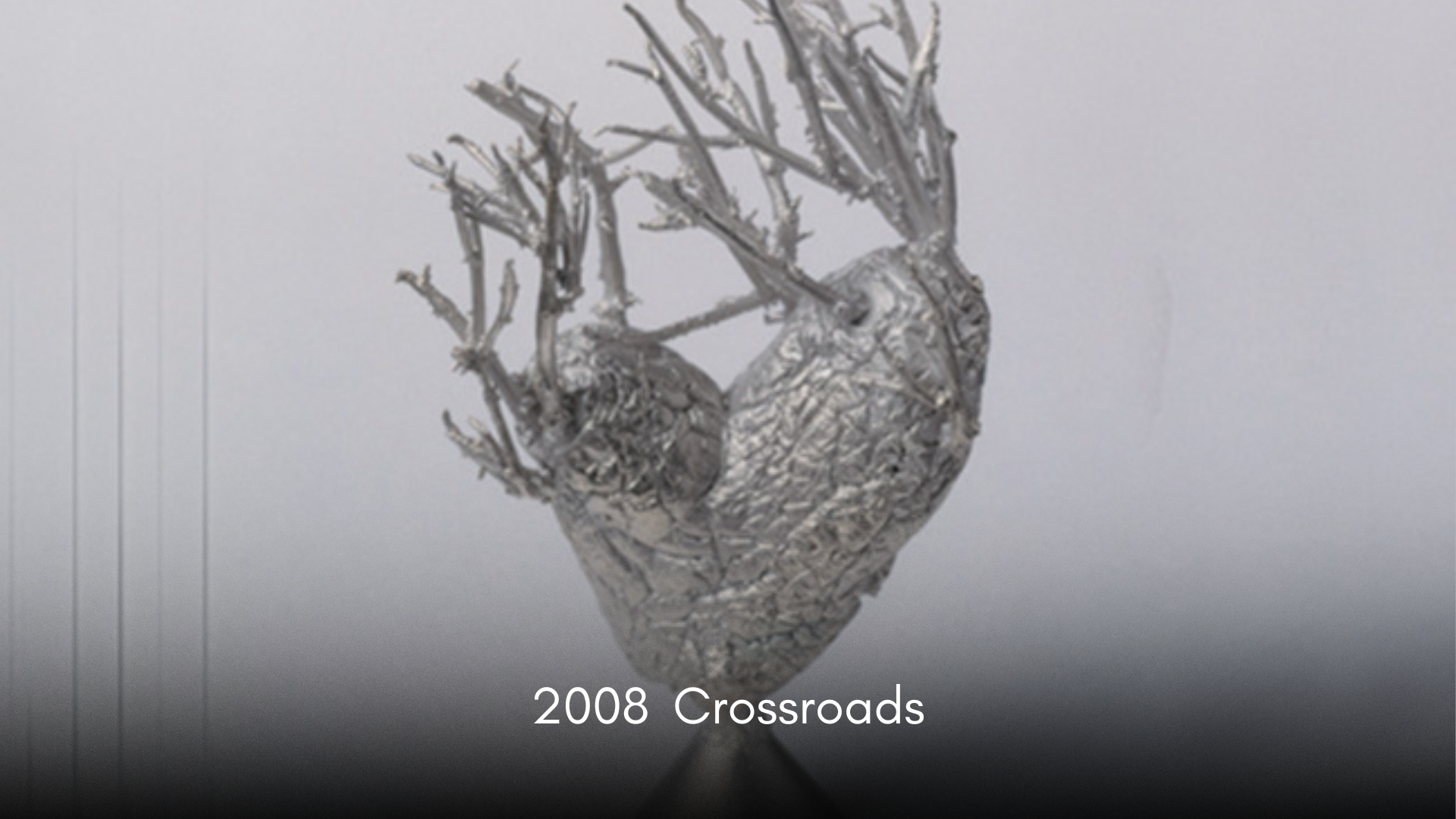 A metallic sculpture resembling a heart with tree-like branches extending from the top, titled '2008 Crossroads'.