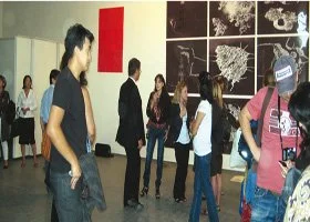 People viewing art and photographs displayed on gallery walls.