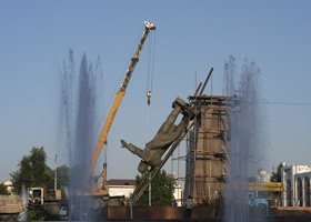 Dismantling a large tower with a crane, water jets spraying around the structure.