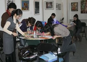 Group of people gathered around a table engaging in a creative activity in an art gallery or studio