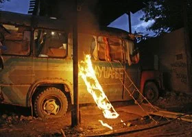 A vehicle is on fire, with flames coming out of the front side, during nighttime.