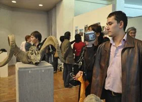 People viewing art displays and sculptures in a gallery or museum.