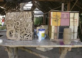 Table with cardboard boxes, wooden blocks, a bucket, and other miscellaneous items in an outdoor setting.