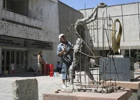 Statue of Lady Justice with a sword and scales, surrounded by a metal frame, outdoors.