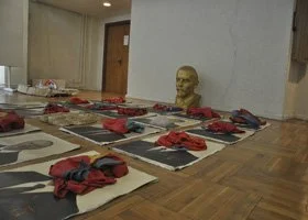 Display of traditional Japanese meal setup with red table settings, a bust statue, and tatami mats.