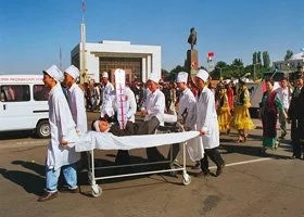 Artists in a procession, outdoors near a government building, under a clear blue sky.
