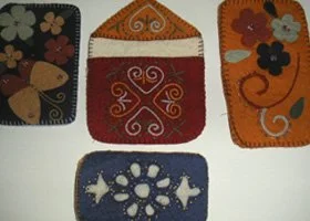 Four colorful felt pouches with embroidered designs, including a butterfly, floral patterns, and decorative swirls.