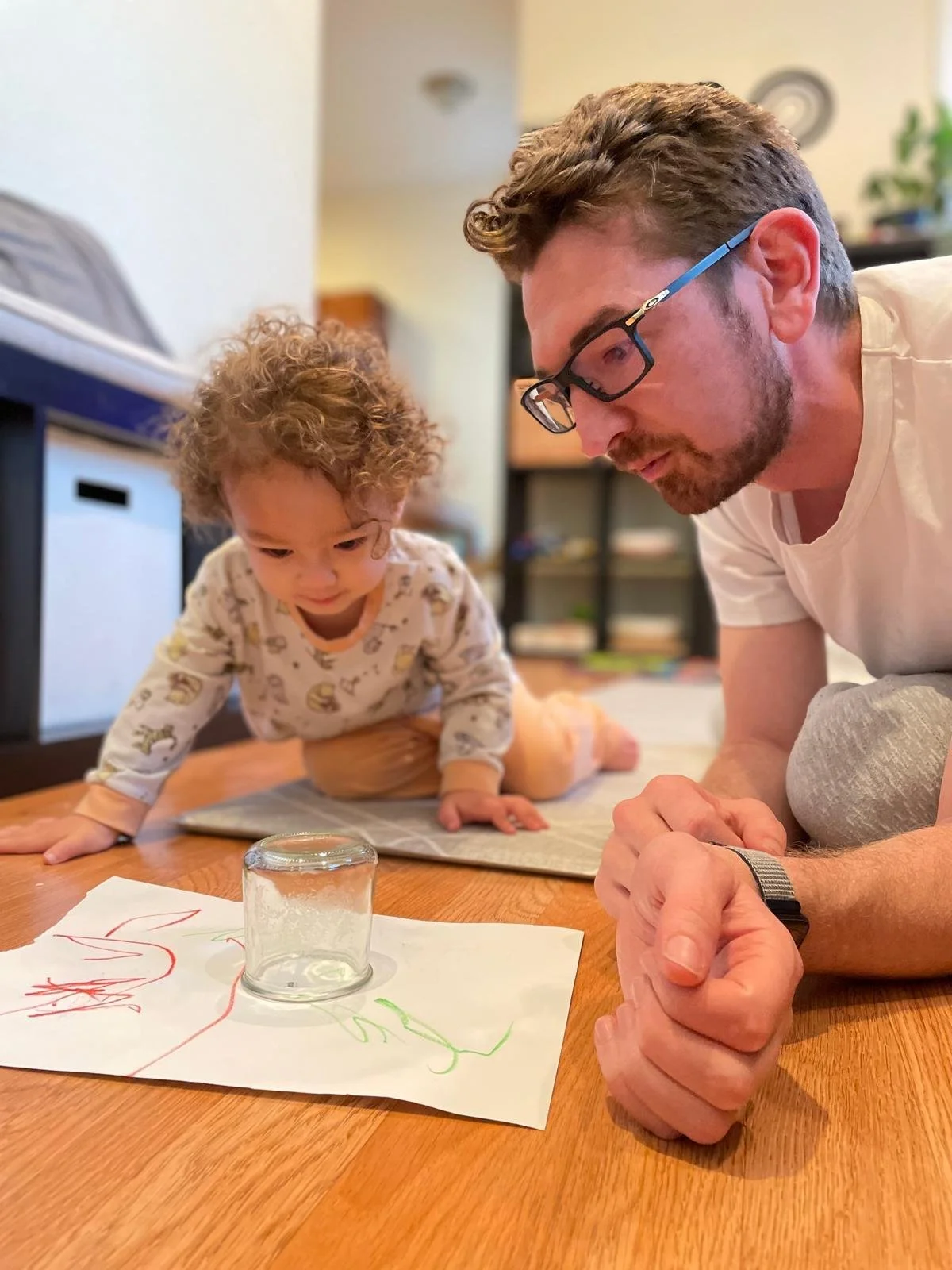 Woman sitting on a bench, writing in a notebook, next to an abstract art painting leaning against the wall.