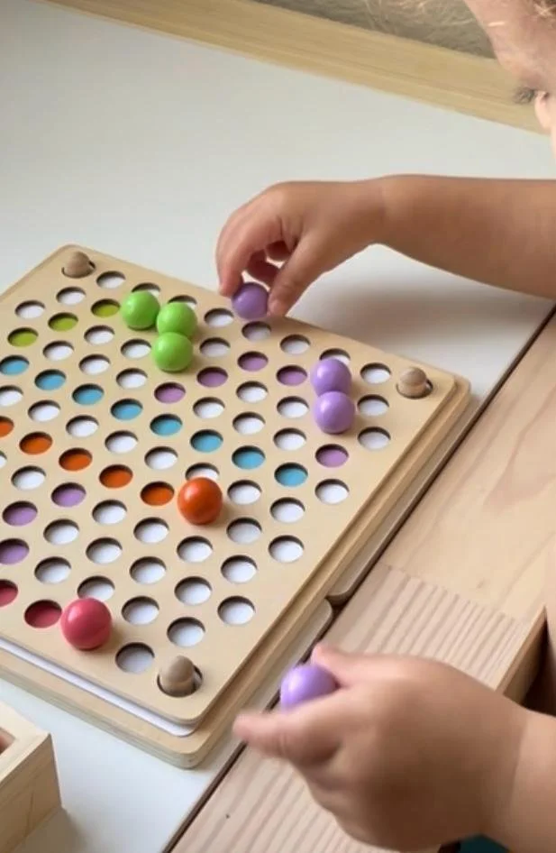 Child playing Connect Four with purple, green, orange, and pink game pieces on a wooden board.