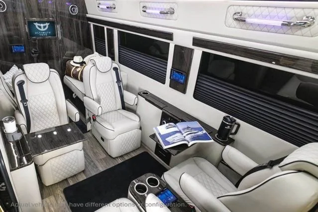 Luxury interior of a private jet with white leather seats, a black table, and windows along the side.