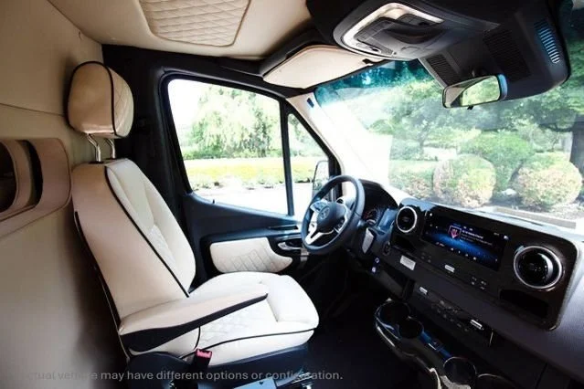 Interior of a vehicle, showing the driver's seat, steering wheel, and dashboard with a digital display.