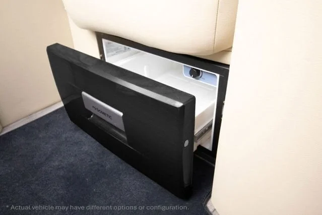 Open pull-out drawer in a wall, revealing a safe inside, located next to a beige couch.