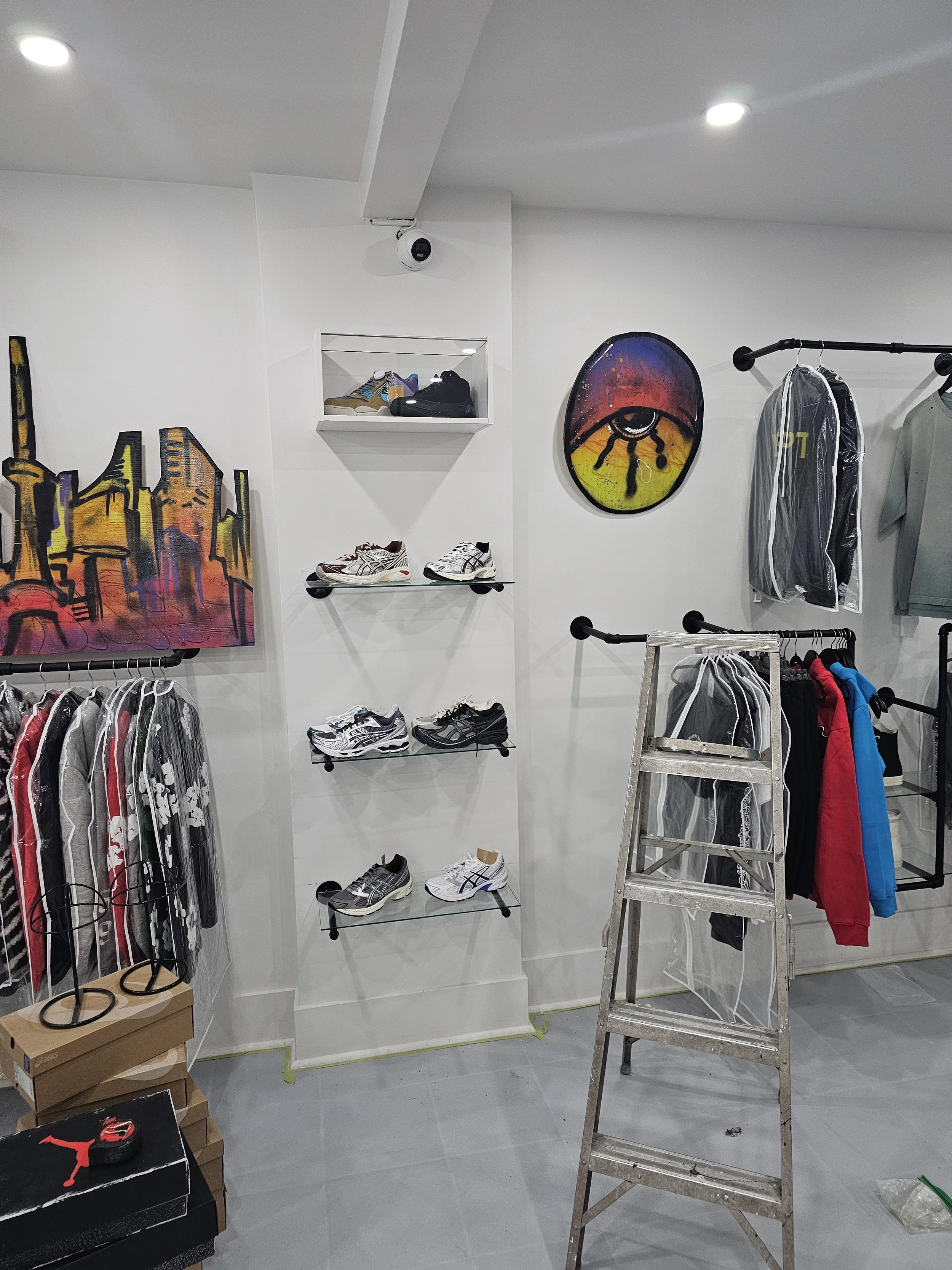 Inside a retail clothing store, display shelves and clothes racks that he installed.