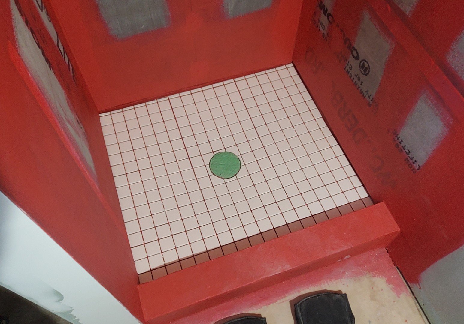Red fire hydrant box with a tiled interior floor and a green valve in the center.