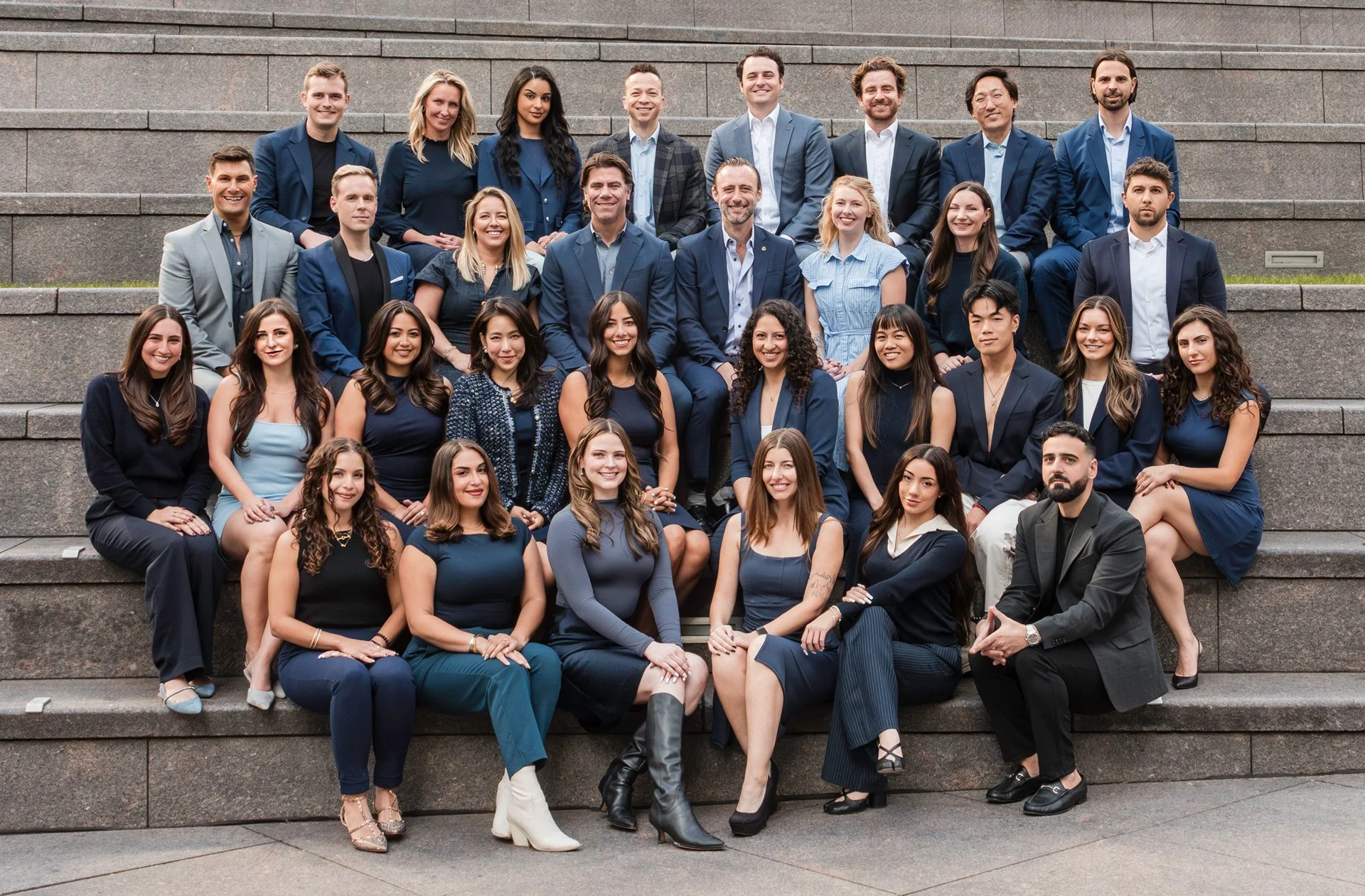 A large group of professionally dressed people posing on steps outdoors for a group photo.