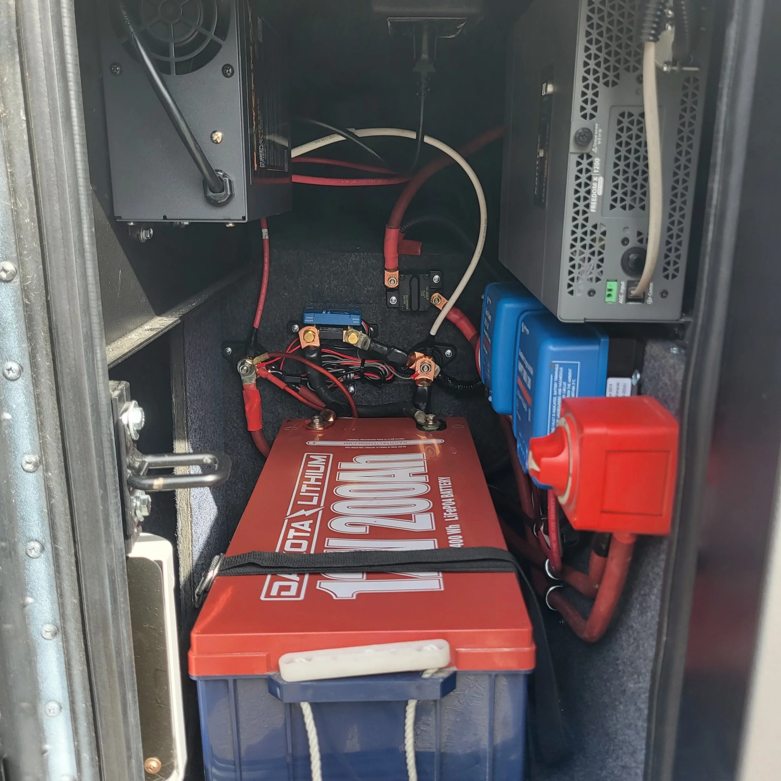 Interior view of a battery compartment with a large red lithium-ion battery, wiring, and electronic components.