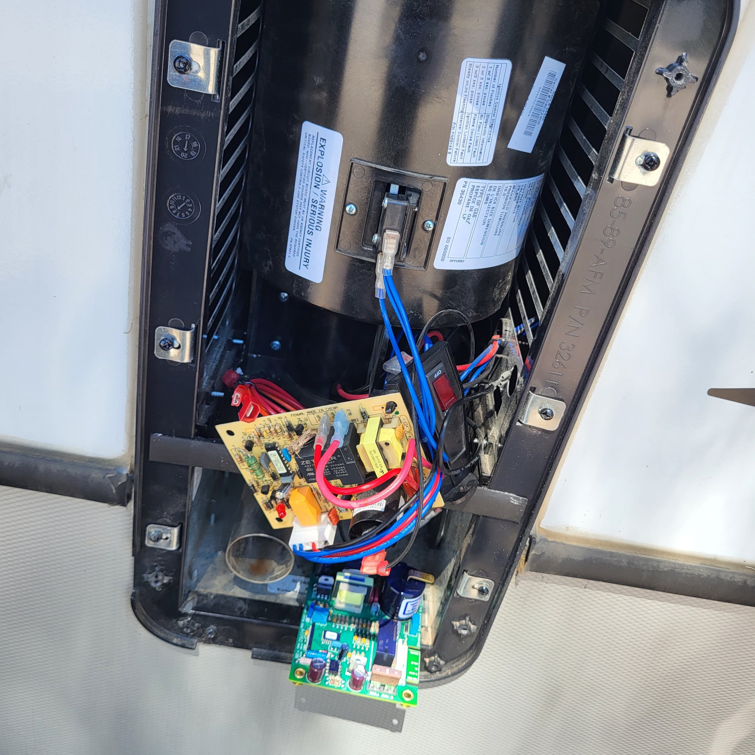 Open ceiling air conditioning unit showing internal components including a circuit board, wiring, and the compressor.
