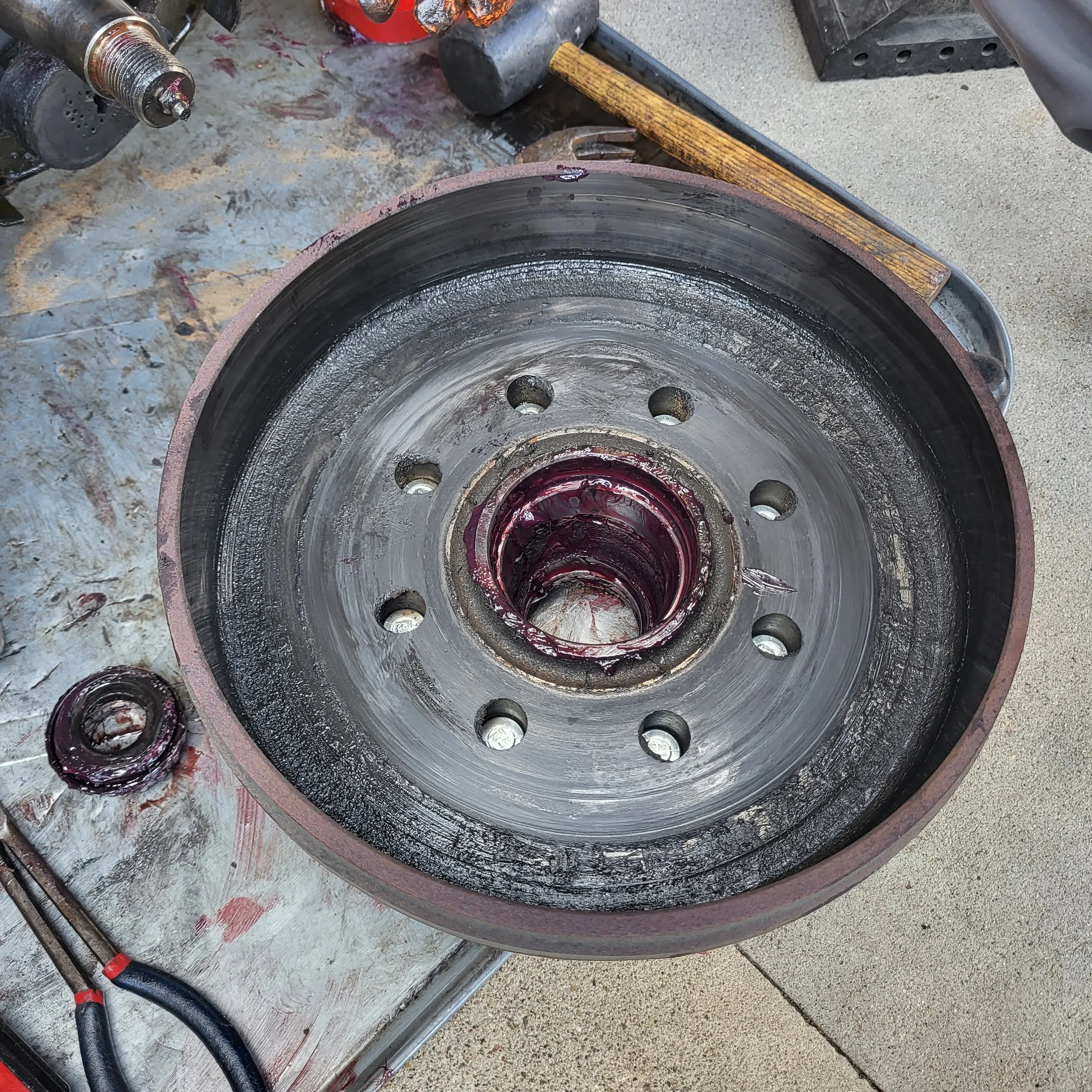 Close-up of a large mechanical wheel with grease, surrounded by tools and workbench in workshop.