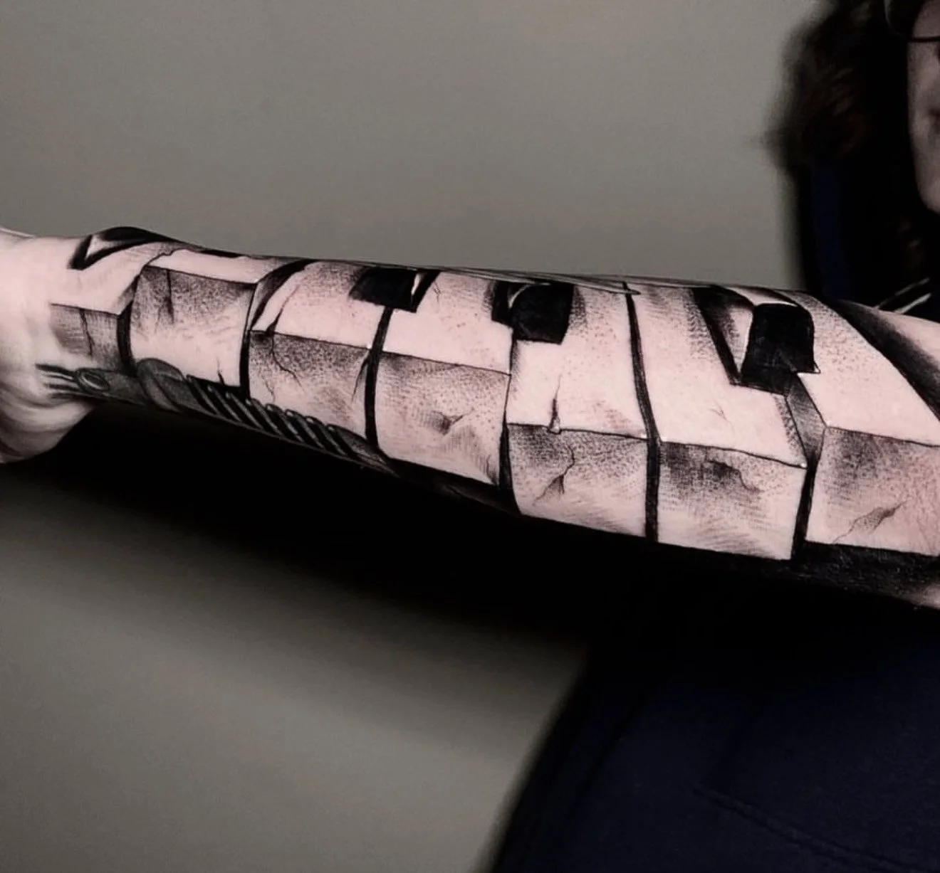Black and grey tattoo of broken piano keys on the lower arm, created by Cody Eckenrode at CREate Tattoo Studio.