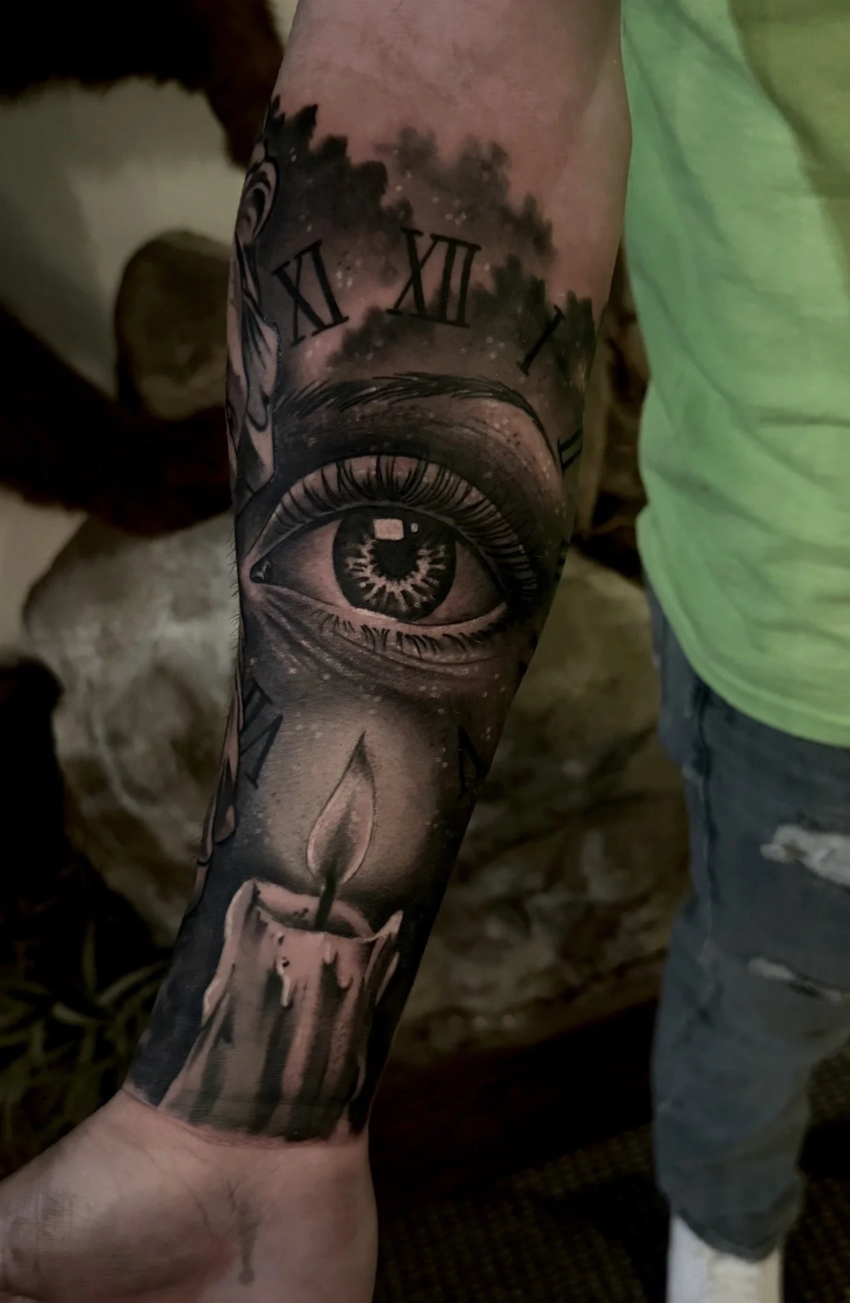 Black and grey tattoo titled “Letting Time Burn Away,” featuring a candle, a clock with Roman numerals, and an eye done by Cody Eckenrode at CREate Tattoo Studio.