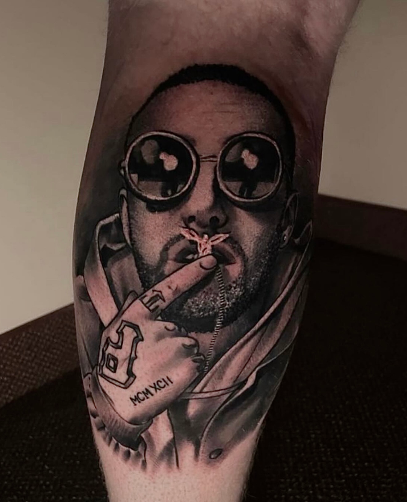 Black and grey tattoo of Mac Miller smoking a joint while wearing sunglasses, created by Cody Eckenrode at CREate Tattoo Studio.